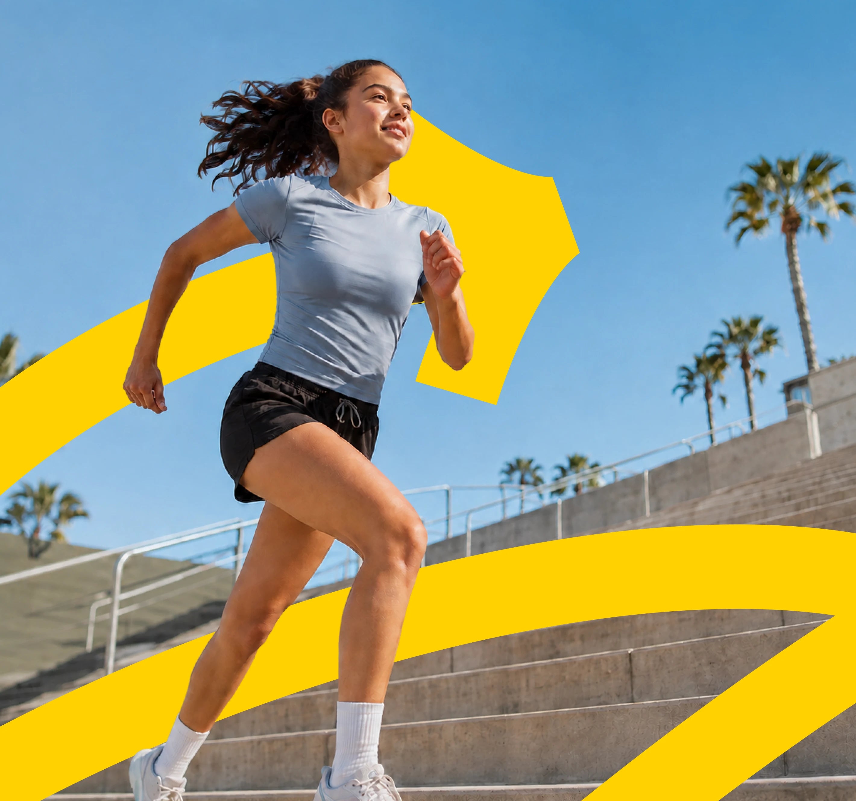 A teenage girl running up outdoor stadium steps in the sunshine.