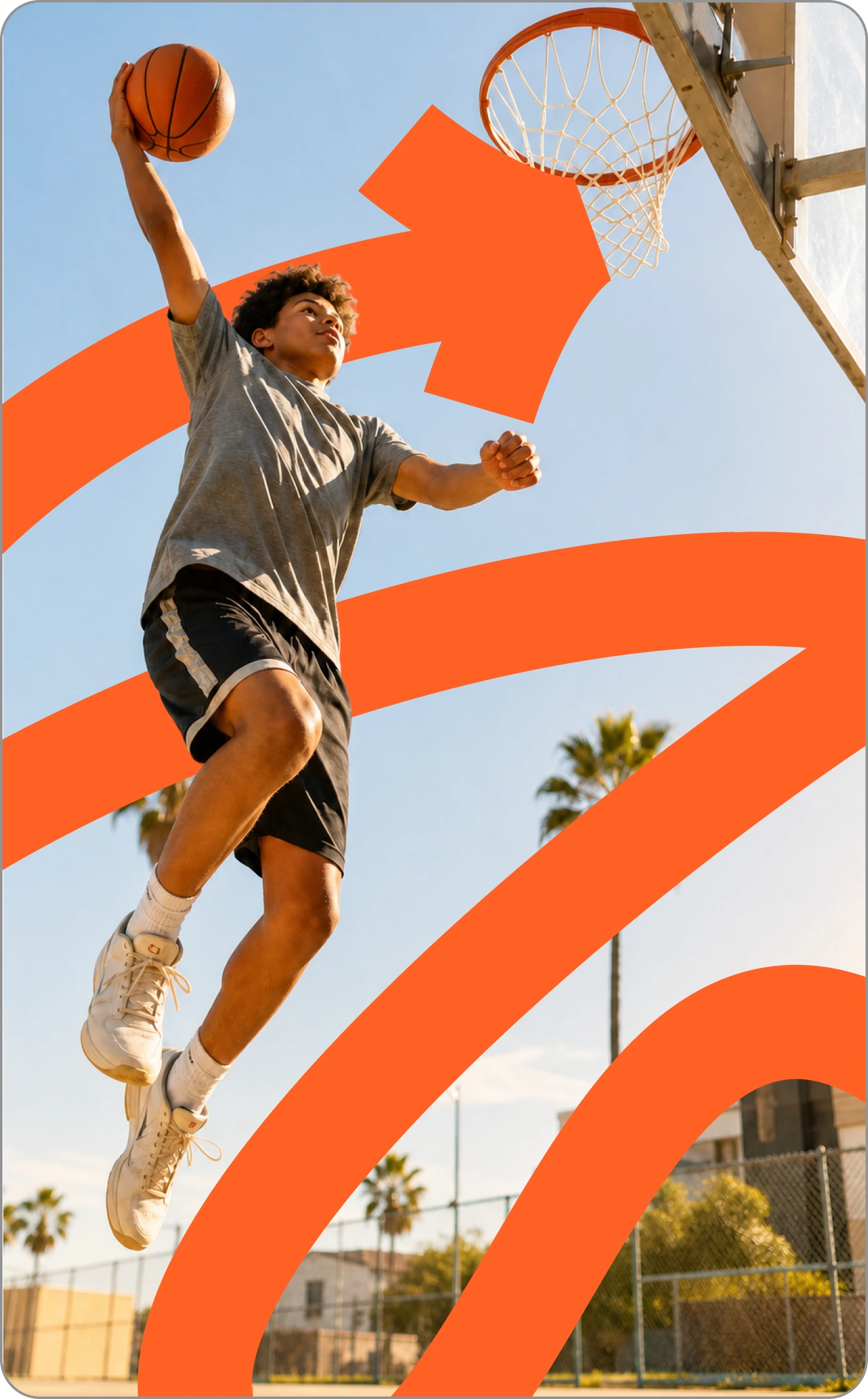 Teen boy dunking a basketball on an outdoor court.